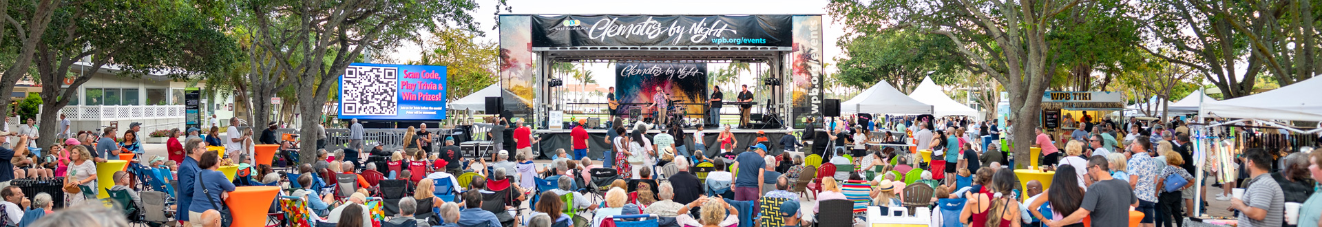 Large crowd surrounding Clematis by Night stage, flanked by LED screen and food vendor tents, with the waterfront visible in the background.