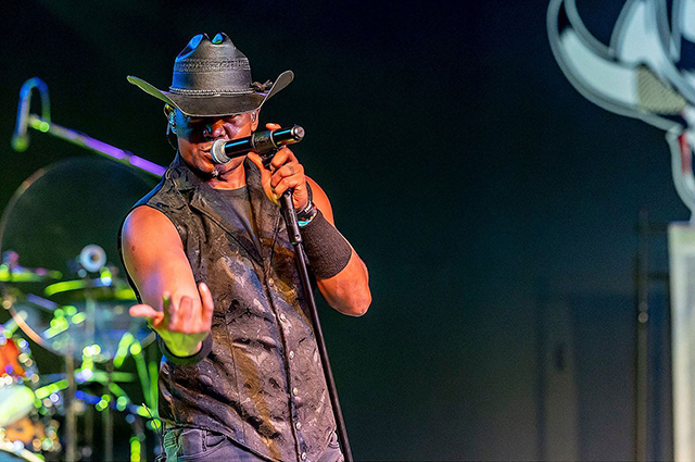 Crossfire Creek Band lead vocalist wearing cowboy hat, singing into microphone, looking toward viewer