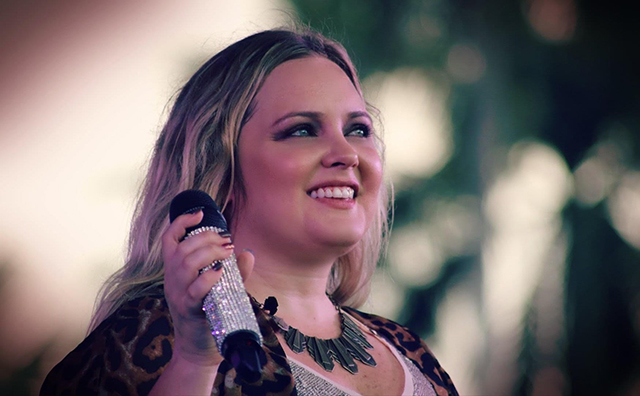 Close-up image of Samantha Russell smiling, holding microphone