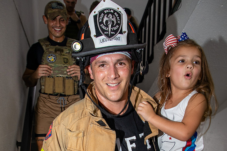 West Palm Beach Firefighters carries his child down the stairs - aa