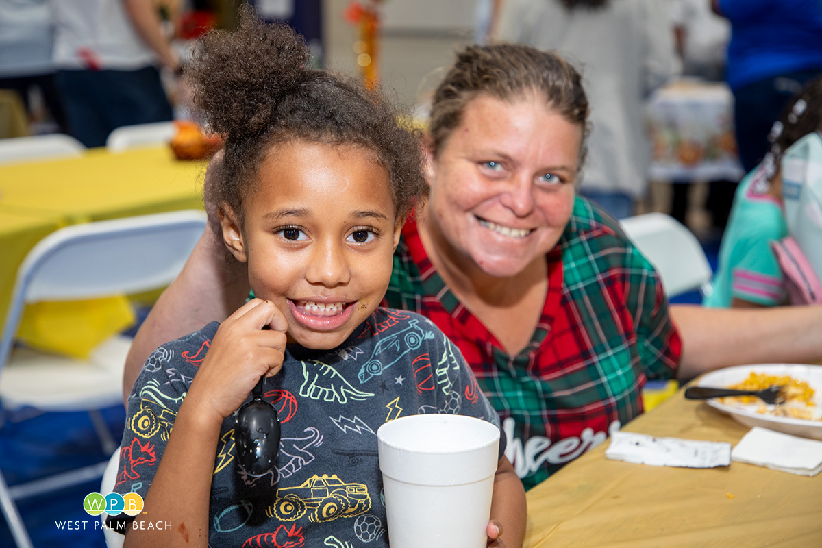 Child with beaming smile as mom looks on - a