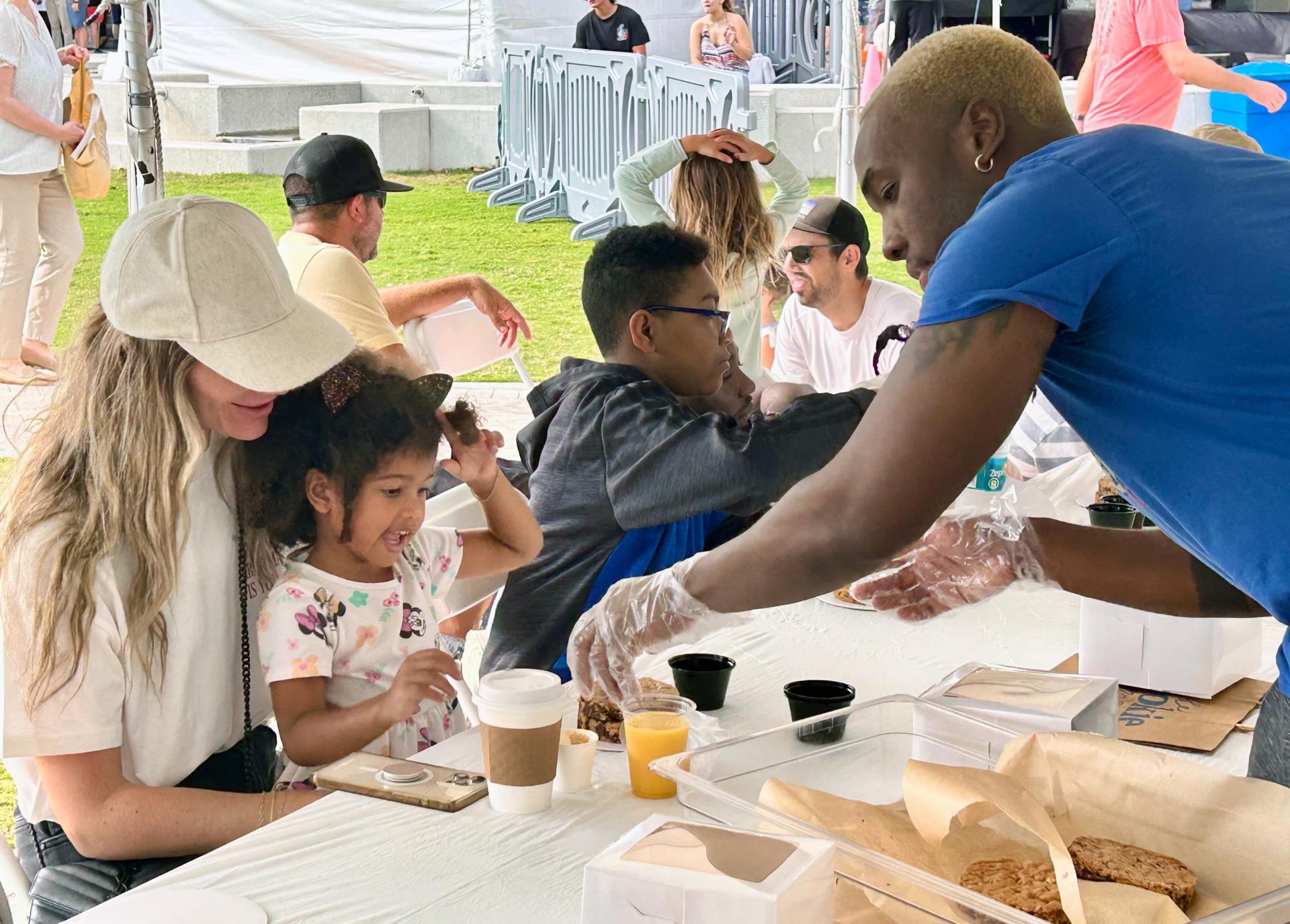 Kookie Box owner Ty Russell helps child and mother make a cookie