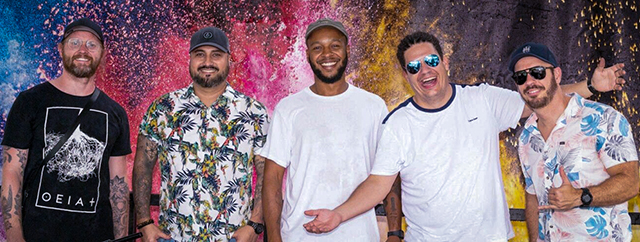 5 members of the band PRATO posed in front of a colorful mural