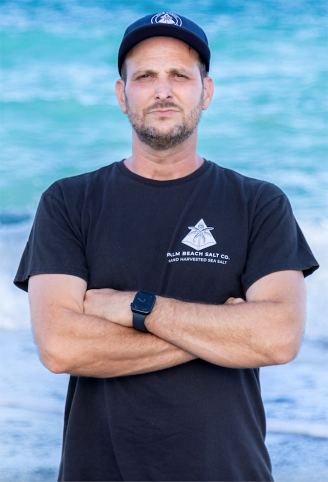 Portrait of Chef Jonathan Richards, arms crossed, with ocean waves in background.