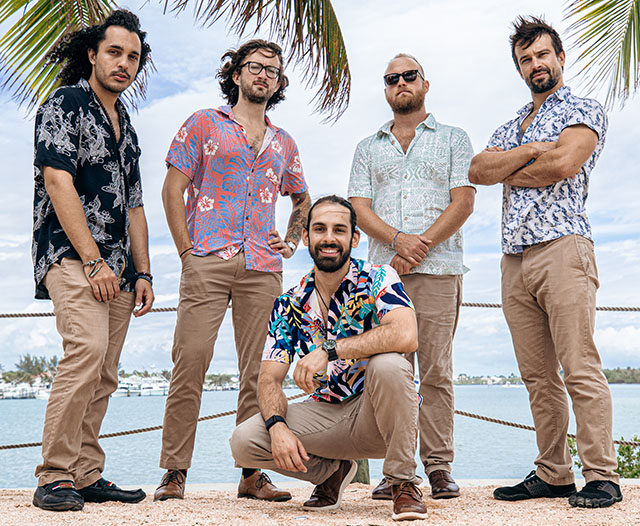 Photo of Joey Calderaio band on the beach with palm trees and ocean in background.