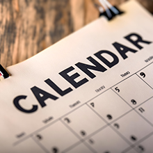 Close image of a generic calendar with CALENDAR in bold at the top, on a wooden counter