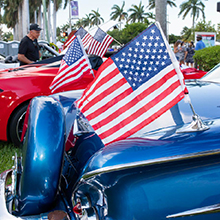 Photo of vintage cars in red and blue flying American flag.