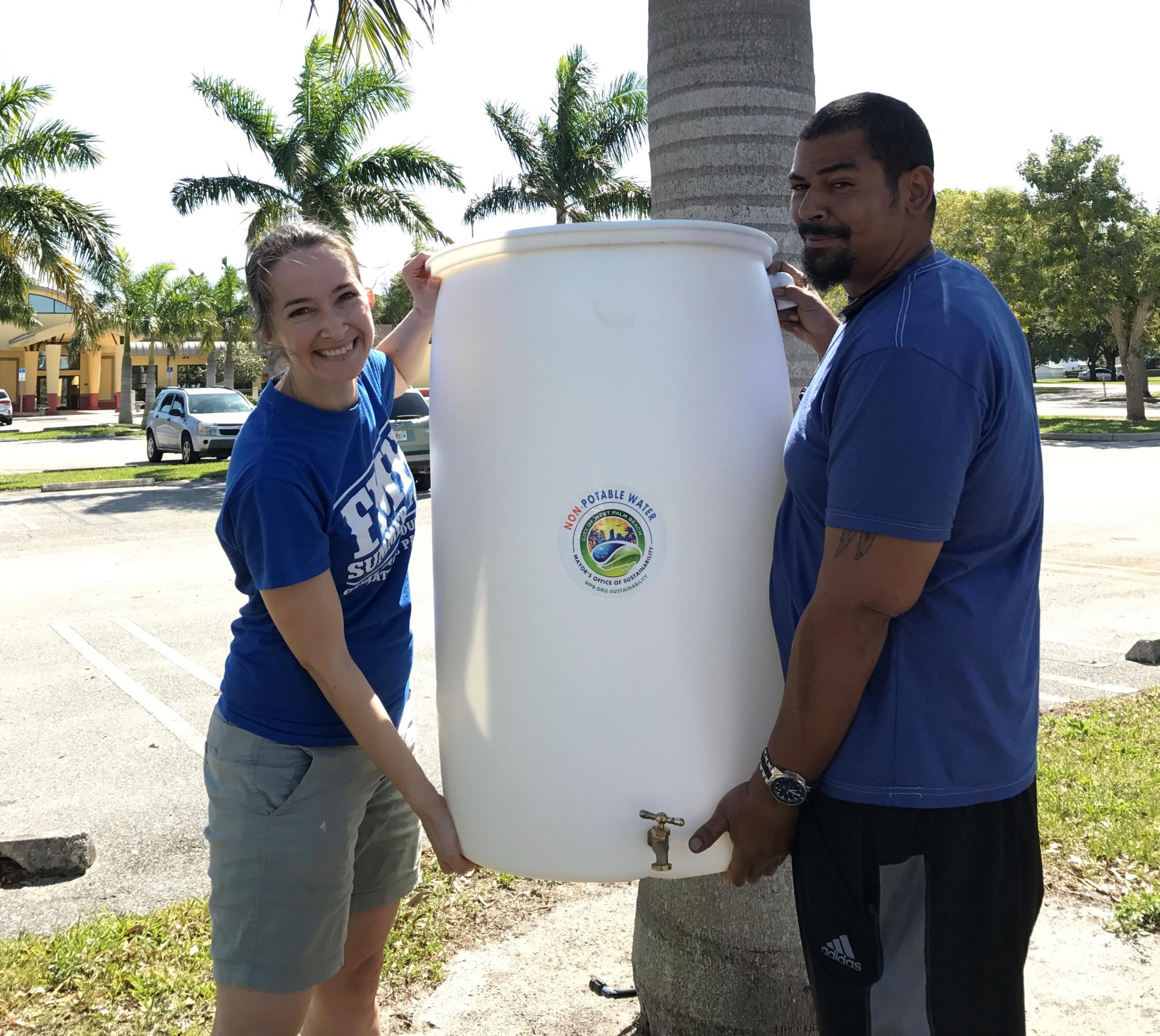 Two people holding a rain barrel after workshop