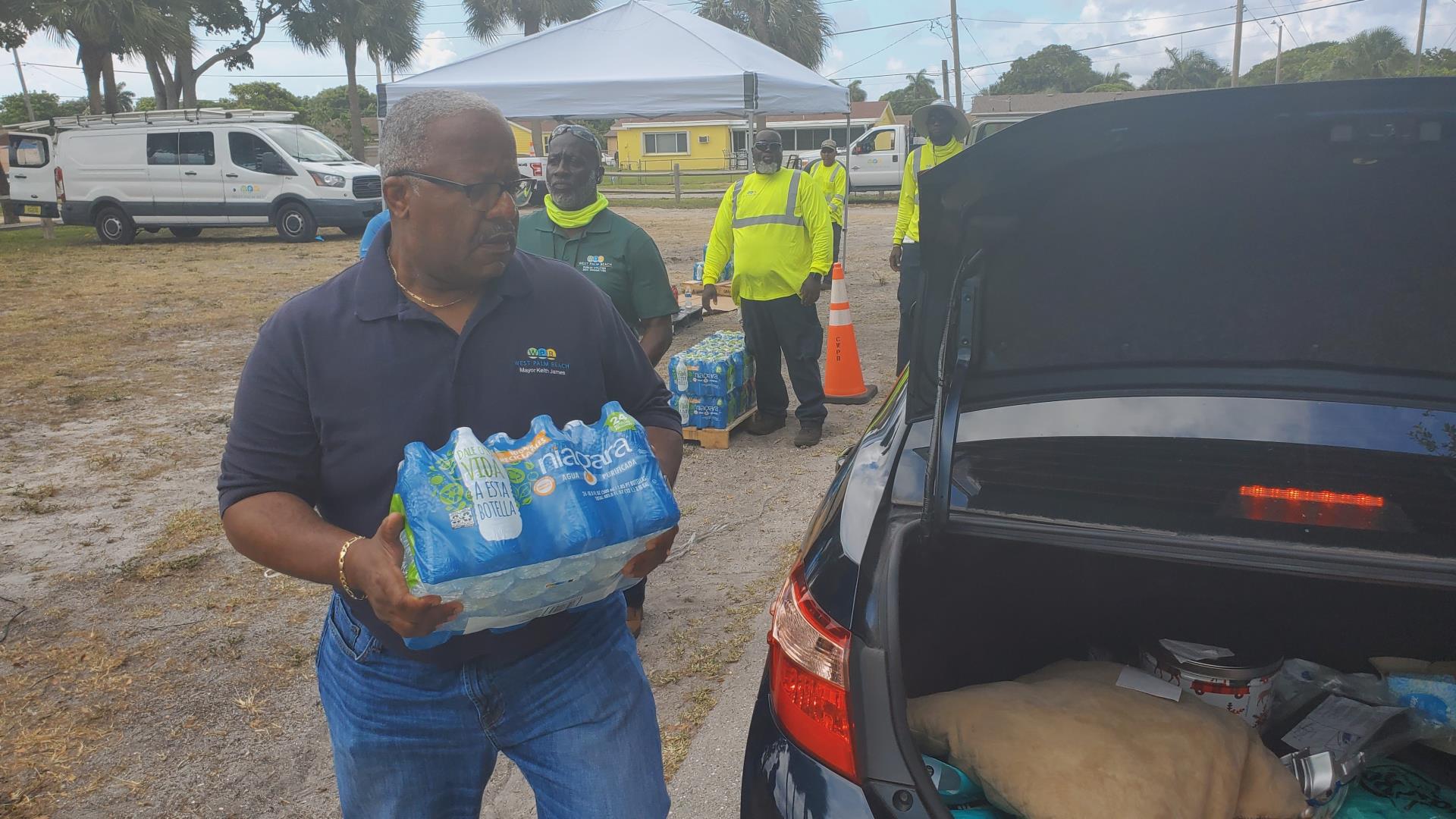 Mayor Keith A. James loads drinking water into the cars of residents from the City distribution point in Gaines Park Monday