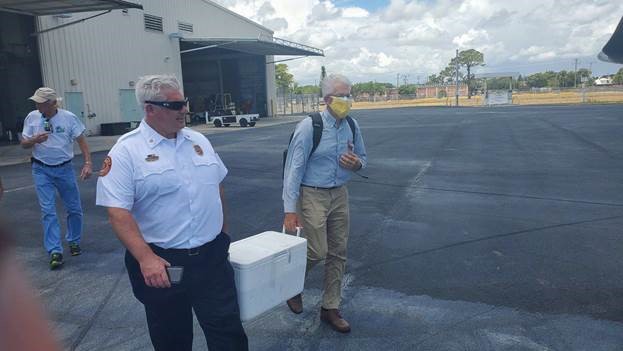 Bound for FDEP in Tallahassee, lab samples are carried across the tarmac at PBIA by City of West Palm Beach Asst. Fire Chief Brent Bloomfield and Public Utilities Laboratory Manager John Maxted